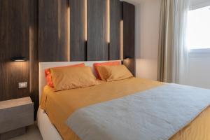 a bedroom with a large bed with orange pillows at Portopiccolo Avolare Apartments in Borgo, beach included in Sistiana