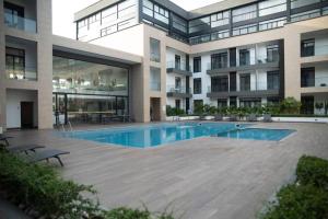 a large building with a swimming pool in front of it at Pool View Apartment @Embassy Gardens in Cantonments