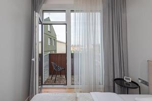 Schlafzimmer mit einem Bett und einem großen Fenster mit einem Balkon in der Unterkunft Comfortable 1 BD Old Town Apartment by Hostlovers in Kaunas