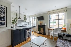 uma cozinha com armários azuis e uma sala de estar em Lovely 1BR Flat, Prime Location Bloomsbury, Euston em Londres