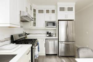 a kitchen with white cabinets and a stainless steel refrigerator at Vancouver Retreat Upper Suite with Living Room or Basement Suite Room Only in Vancouver