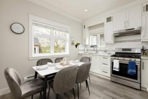 een witte keuken met een tafel en stoelen en een fornuis bij Vancouver Retreat Upper Suite with Living Room or Basement Suite Room Only in Vancouver