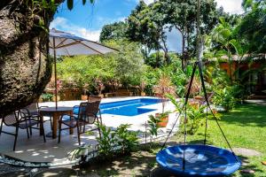 patio ze stołem, parasolem i basenem w obiekcie Casas Natureza Brasil w mieście Arraial d'Ajuda