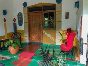 una puerta delantera de una casa con sillas y plantas rojas en A Place of True Colors, en Pottuvil