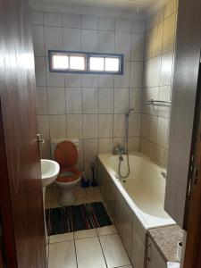 a bathroom with a toilet and a tub and a sink at New Joy in Bloemfontein