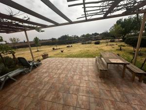 a patio with a wooden table and benches and a field at New Joy in Bloemfontein