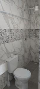 aseo blanco en un baño con paredes de mármol en Hospedagem Central Eu Amo Piri, en Pirenópolis