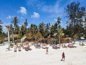una playa con un montón de sillas y palmeras en The Nest Boutique Resort, en Paje