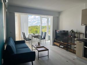 a living room with a couch and a tv and a table at Тристаен апартамент Park View in Targovishte