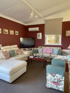 a living room with couches and a flat screen tv at Strahan Wilderness Lodge in Strahan