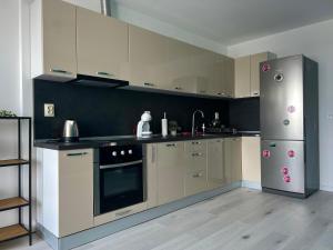 a kitchen with white cabinets and a stainless steel refrigerator at Тристаен апартамент Park View in Targovishte