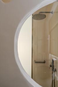 a bathroom with a white mirror and a shower at Belvedere Suites in Firostefani