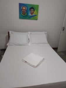 białe łóżko z 2 poduszkami i zdjęciem na ścianie w obiekcie hostel barra w mieście Salvador