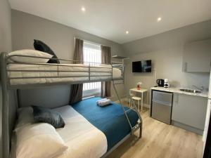 a bedroom with two bunk beds and a kitchen at Holloway Suites - Next To Emirates Stadium - Private Bathroom - Shared Kitchen in London