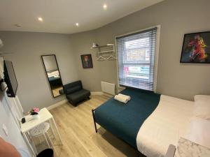 een slaapkamer met een bed, een stoel en een raam bij Holloway Suites - Next To Emirates Stadium - Private Bathroom - Shared Kitchen in Londen