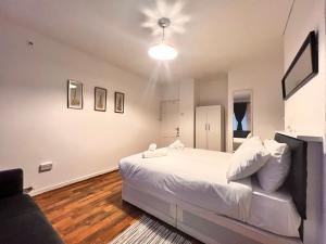 - une chambre avec un grand lit blanc et un canapé dans l'établissement Rooms in Bethnal Green, à Londres