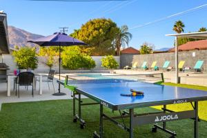 a ping pong table in the yard with an umbrella at Palm Springs Life in Palm Springs