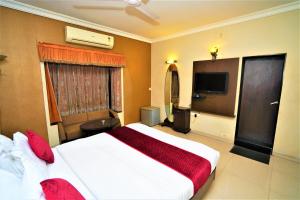 una camera con un grande letto e una televisione di New Hotel Europa Inn a Rajkot