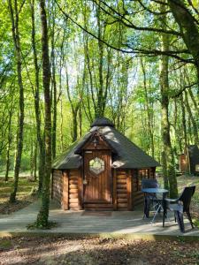 a small wooden cabin in the woods with a table at Le Domaine Insolite de Brocéliande in Paimpont