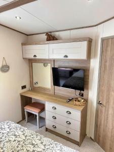 una camera da letto con cassettiera, TV e letto di Hot Tub Lodge Cornwall - Meadow Lakes Holiday Park a St Austell