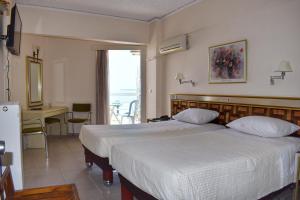 sypialnia z 2 łóżkami, stołem i biurkiem w obiekcie Hotel Theoxenia w mieście Missolungi