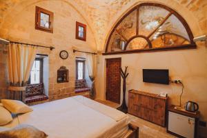 1 dormitorio con 1 cama y TV en la pared en Hanedan Konağı Butik Otel Deluxe Triple Room with Turkish Bath Marvina en Mardin