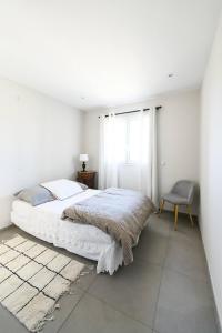 een witte slaapkamer met een bed en een stoel bij Room in a farmhouse - private bathroom - by feelluxuryholidays in Vacqueyras