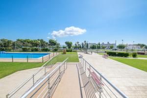 une rangée de bancs dans un parc avec une piscine dans l'établissement Casa Gemma, à Alcanar