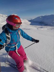 a young girl is skiing down a snow covered slope at Idyllisk hus med sauna og jacuzzi, Lyngen in Nord-Lenangen