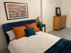 a bed with orange and blue pillows in a bedroom at Stunning and Spacious 2bed flat in central Woking in Woking