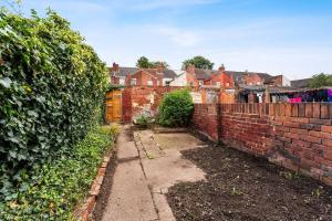 a brick wall next to a yard with houses at Sophisticated 2 bed in Doncaster sleeps 6! in Balby