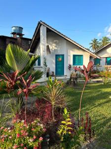 uma casa branca com uma porta azul e algumas plantas em Chalés Jardins dos Cajueiros em Tamandaré