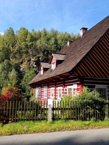a red and white house with a wooden fence at Mlýn u skály in Deštné v Orlických horách