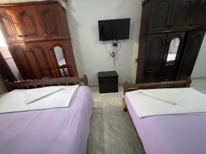 1 dormitorio con 2 camas y TV en la pared en Bakar house, en Asuán