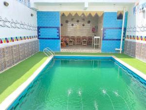 Bakar house في أسوان: حمام سباحة في غرفة ذات بلاط أزرق وأخضر