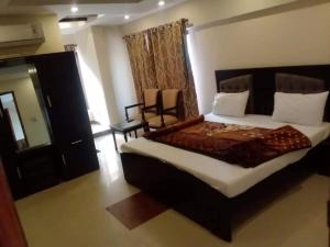 a bedroom with a large bed and a chair at PAK HOTEL Islamabad in Islamabad