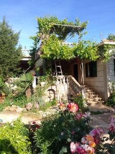 una casa con un jardín con flores y una escalera en Shtepia e Llambros en Vlorë