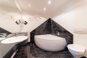 a bathroom with a tub and a toilet and a sink at Hotel Ross in Schweinfurt