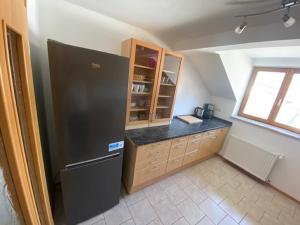 a kitchen with a black refrigerator and wooden cabinets at Ferienwohnung Elip in Essing