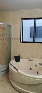a large white bath tub in a bathroom with a window at JOMALEY , Real HOTEL Jomaley in Loja
