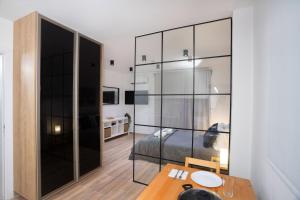STAY Zen Studio في ليماسول: غرفة نوم بسرير وطاولة وجدار زجاجي