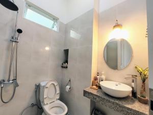 y baño con aseo, lavabo y espejo. en Nạp Homestay en Kinh Dinh