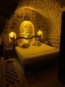 1 dormitorio con 1 cama en una habitación de piedra con reloj en Hanedan Konağı Butik Otel Deluxe Queen Bed Double Room Verdo en Mardin