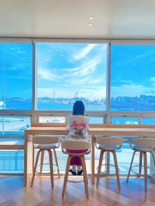 釜山的住宿－Stay Gaon，坐在大窗户前的桌子上的孩子