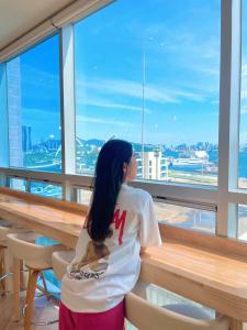 una joven mirando por la ventana de un edificio en Stay Gaon en Busan