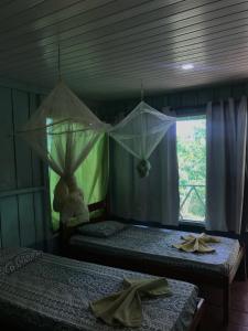 two beds in a room with a window at Ipanema Lodge in Careiro