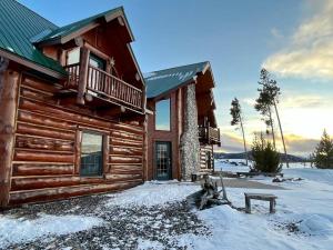 Cabaña de madera con balcón en la nieve en The Wyoming Lodge and Game Room, en Dubois