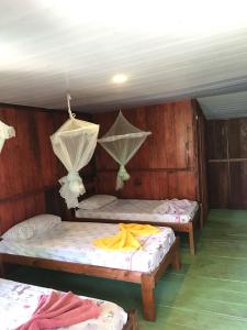 a room with two beds with nets on the ceilings at Ipanema Lodge in Careiro