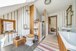 a bathroom with a tub and a toilet and a sink at Amazing Arts & Crafts House in Robertsbridge +49 photos
