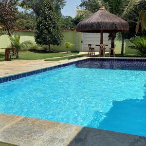 uma piscina com uma mesa e um guarda-sol em Casa dos coqueiros em Pirenópolis